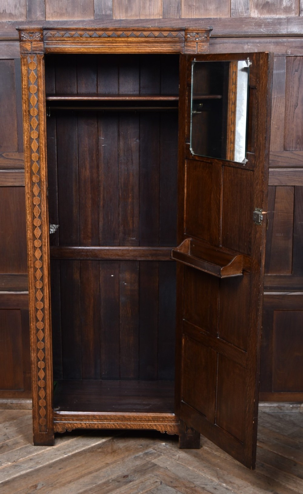 A narrow single-door Edwardian oak hall robe featuring geometric carved borders, a floral relief top panel, and rectangular lower door panels. View V