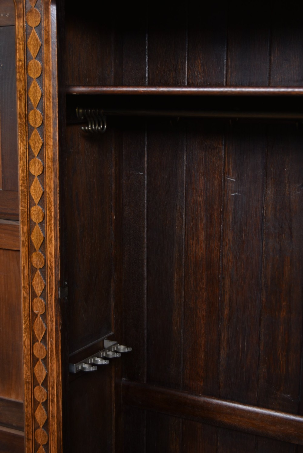 A narrow single-door Edwardian oak hall robe featuring geometric carved borders, a floral relief top panel, and rectangular lower door panels. View VI