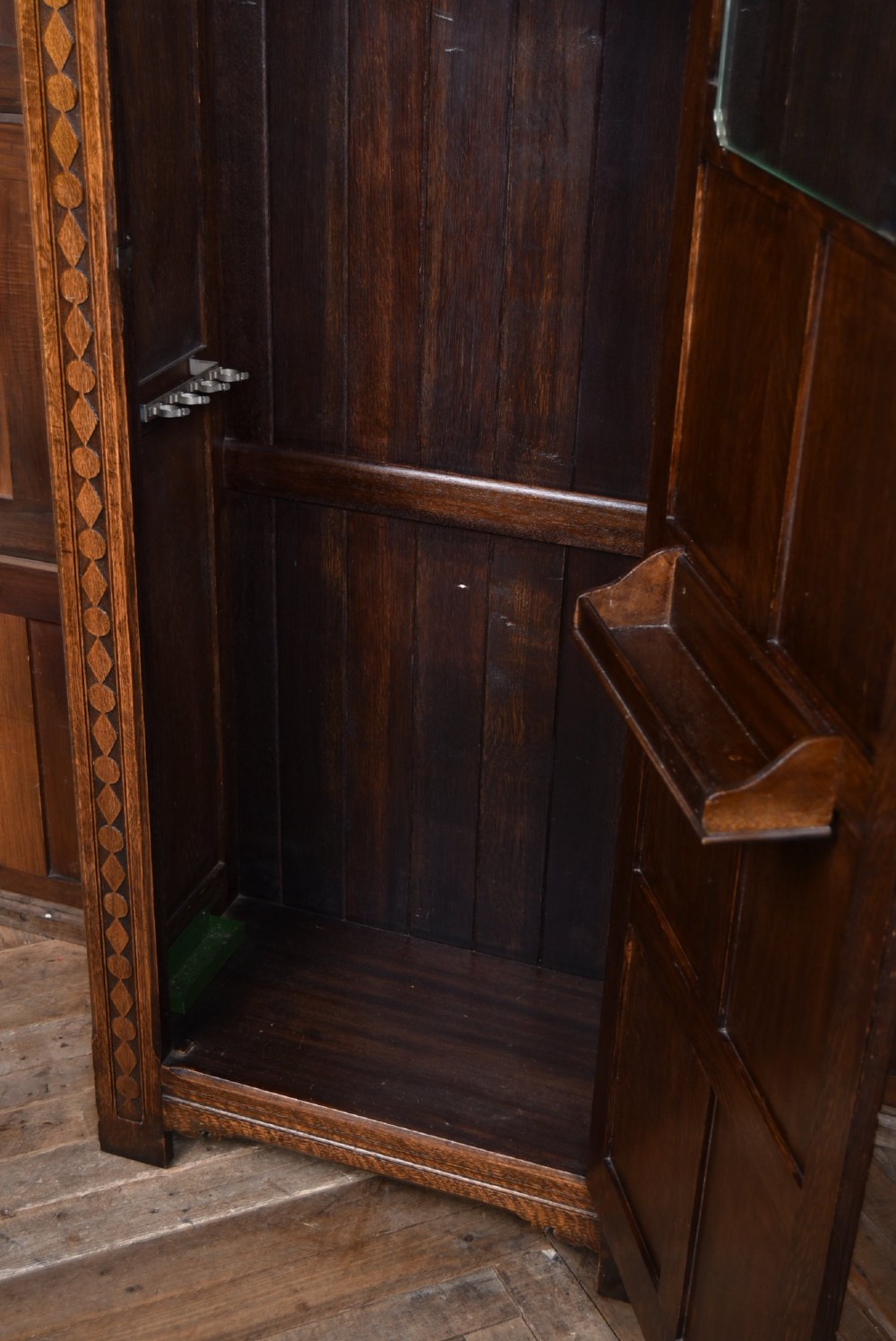 A narrow single-door Edwardian oak hall robe featuring geometric carved borders, a floral relief top panel, and rectangular lower door panels. View VII