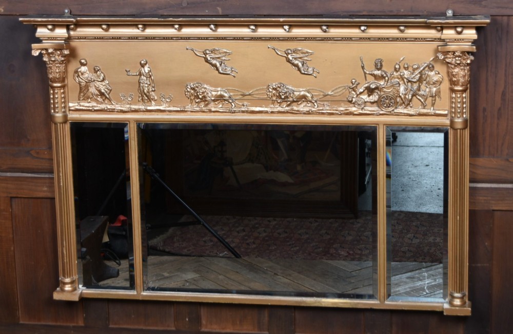 A Regency gilt overmantel mirror featuring a classical relief frieze above three bevelled mirror plates flanked by fluted Corinthian columns.