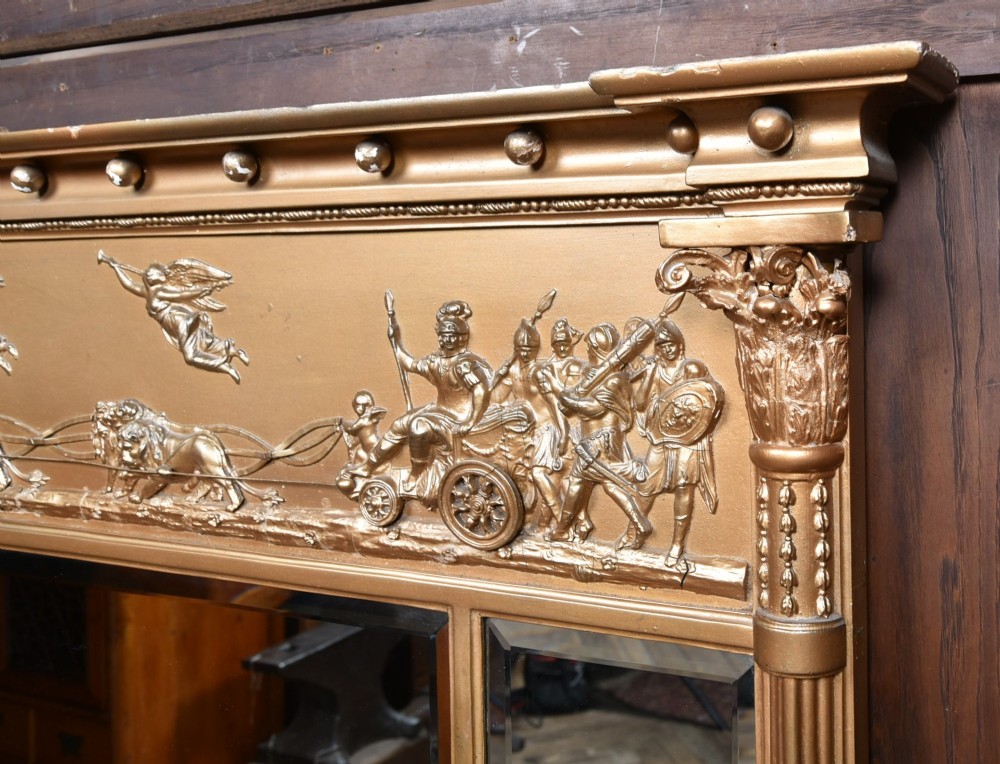 A Regency gilt overmantel mirror featuring a classical relief frieze above three bevelled mirror plates flanked by fluted Corinthian columns. View II