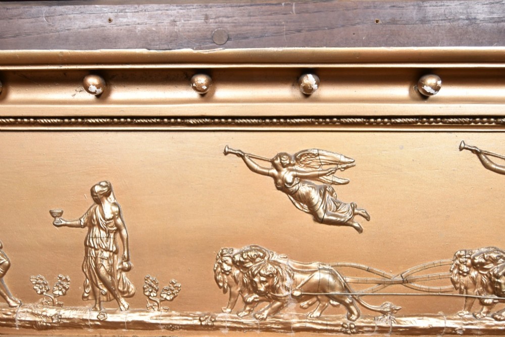 A Regency gilt overmantel mirror featuring a classical relief frieze above three bevelled mirror plates flanked by fluted Corinthian columns. View V