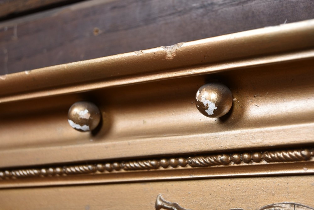 A Regency gilt overmantel mirror featuring a classical relief frieze above three bevelled mirror plates flanked by fluted Corinthian columns. View IX