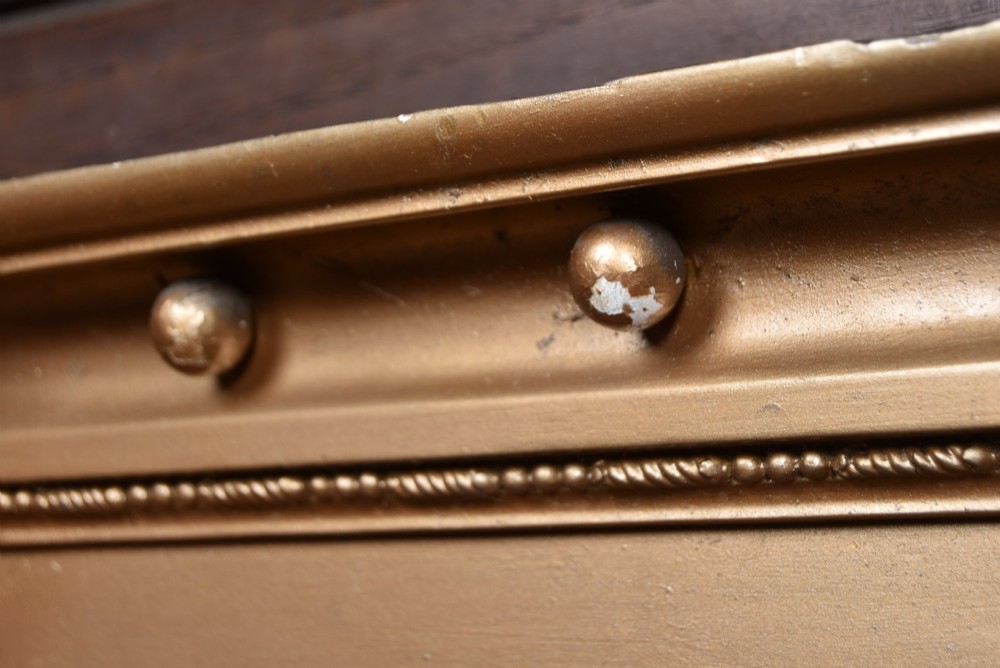 A Regency gilt overmantel mirror featuring a classical relief frieze above three bevelled mirror plates flanked by fluted Corinthian columns. View X