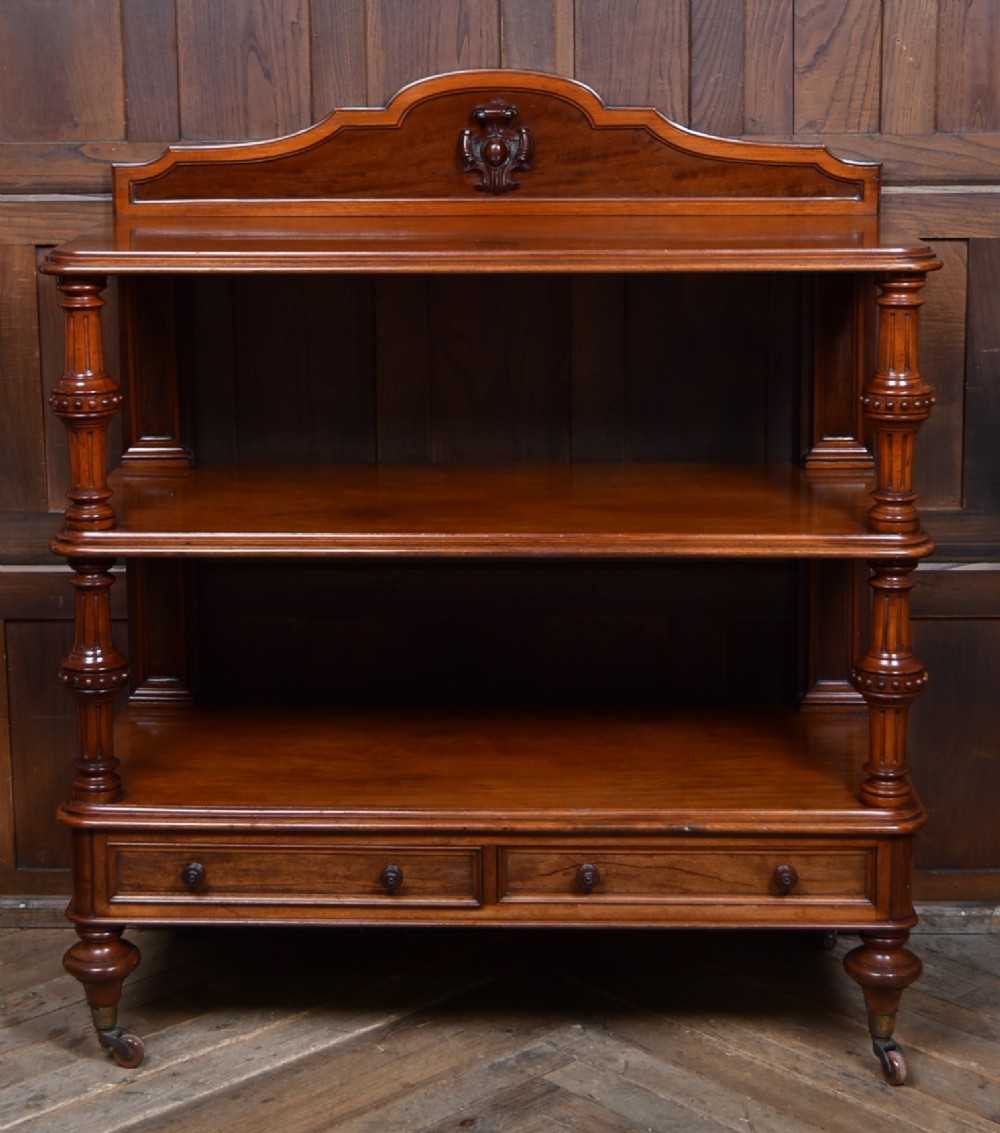 A Victorian mahogany three-tiered whatnot featuring turned column supports, two lower drawers with knob handles, an arched gallery top, and brass castors. View II