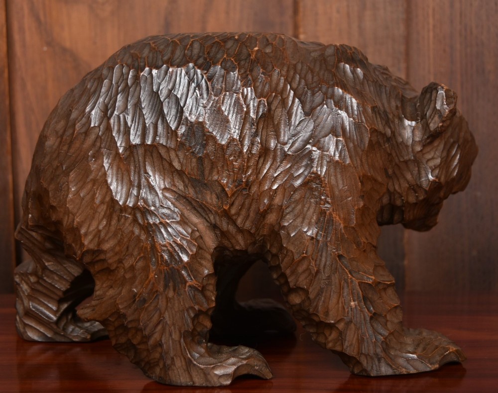 A hand-carved dark wood bear sculpture featuring detailed gouged fur texture and an open mouth. View V