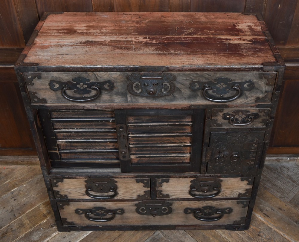 A Japanese tansu wooden chest featuring multiple drawers, sliding louvered doors, a small lockable door, and dark iron corner plates and drop handles. View II