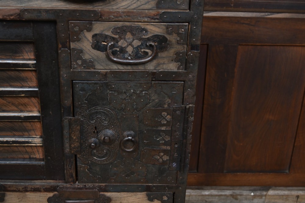 A Japanese tansu wooden chest featuring multiple drawers, sliding louvered doors, a small lockable door, and dark iron corner plates and drop handles. View VI