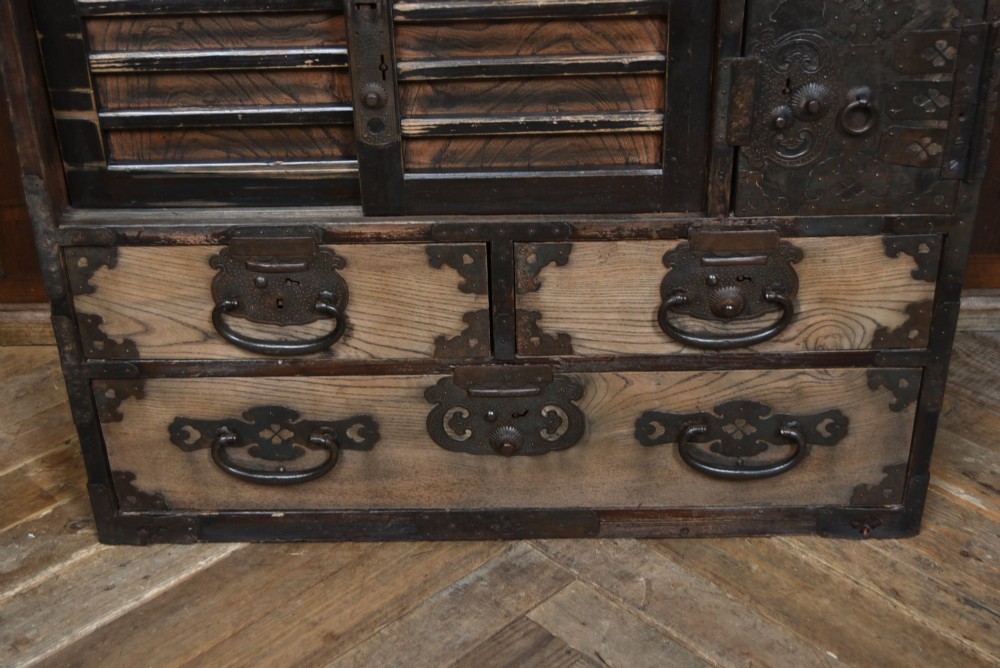 A Japanese tansu wooden chest featuring multiple drawers, sliding louvered doors, a small lockable door, and dark iron corner plates and drop handles. View VII