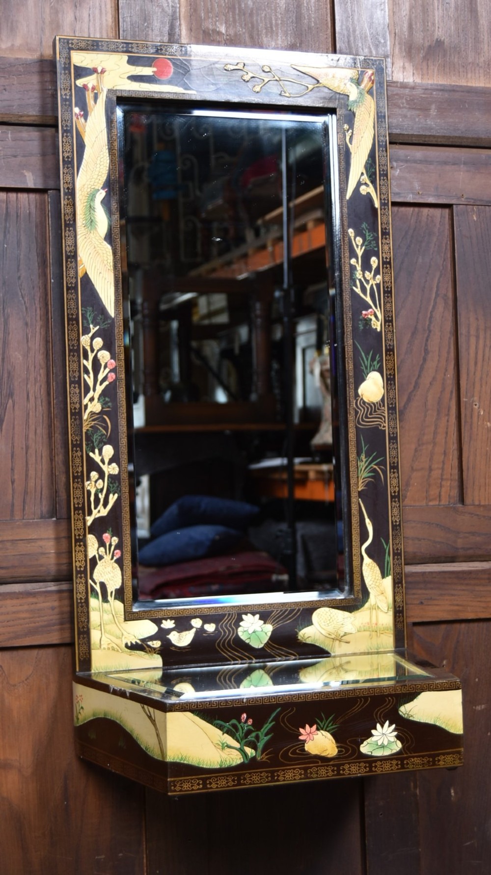A tall black lacquered rectangular wall mirror featuring an integrated bottom shelf and painted borders with cranes, lotus blossoms, and botanical details. View II