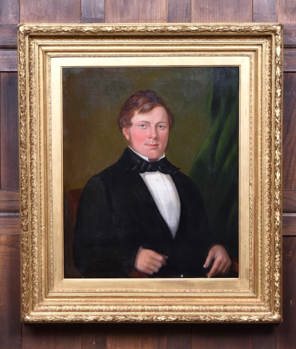 A nineteenth-century oil painting on canvas depicting a seated gentleman wearing a black jacket and white shirt, housed within a gilded wooden frame.