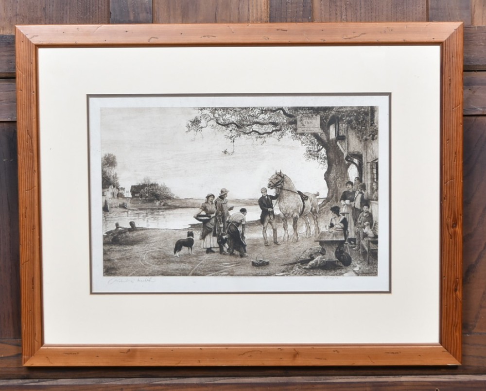 A framed 19th-century monochrome etching depicting figures, a horse, and a dog beside a river outside a village inn, encased in a light wood frame with an off-white mount.