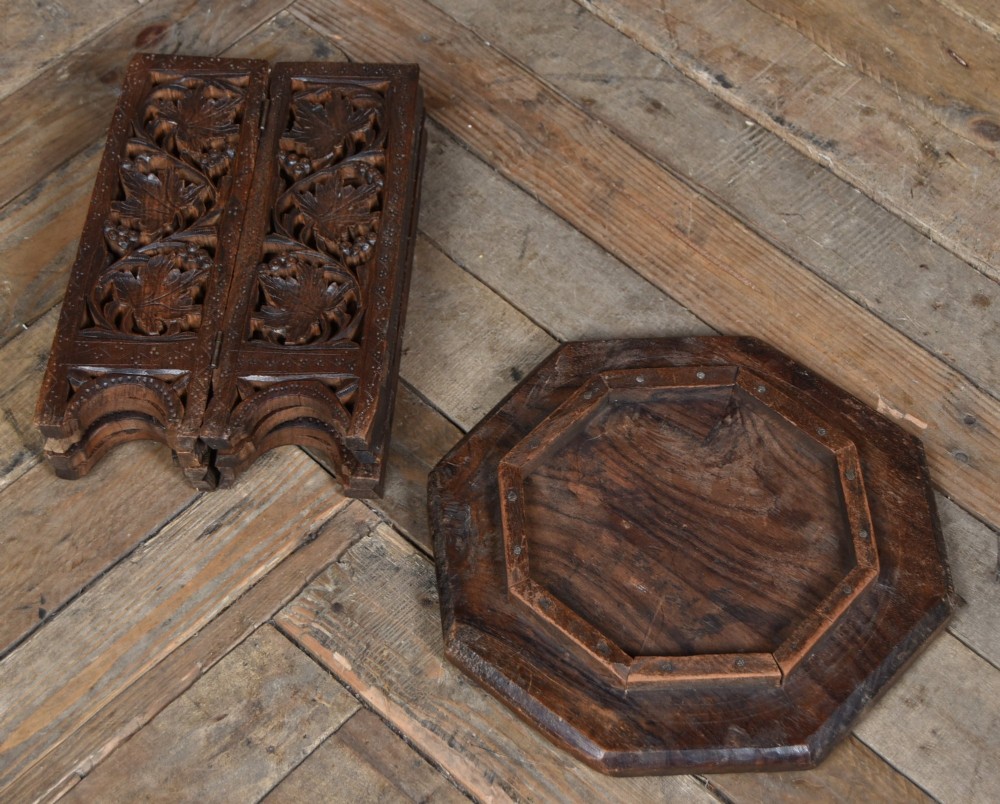 An octagonal dark hardwood side table featuring deep relief foliate carving across the top and openwork pierced panels on the folding base. View VII