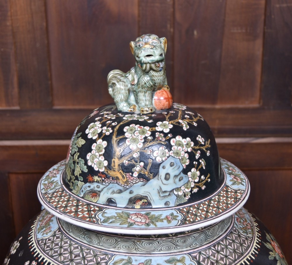 A pair of large black-ground Chinese porcelain floor jars with domed lids topped with foo dog finials and painted peacock, floral, and rockery motifs. View VIII