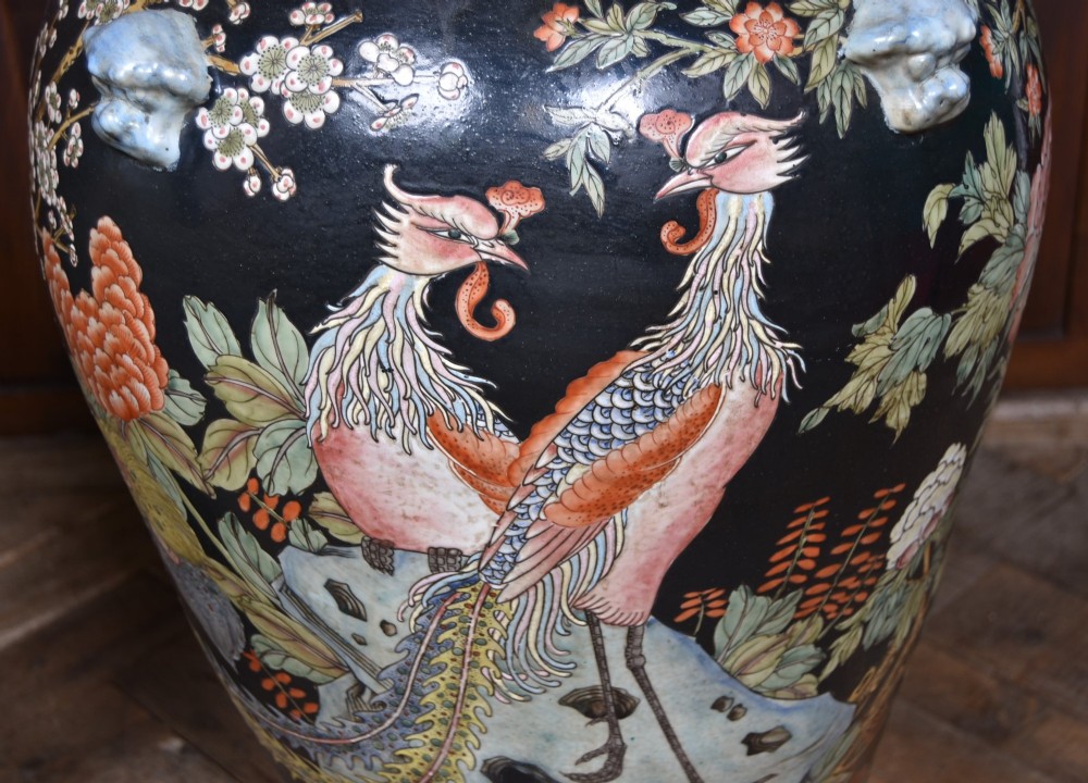 A pair of large black-ground Chinese porcelain floor jars with domed lids topped with foo dog finials and painted peacock, floral, and rockery motifs. View IX