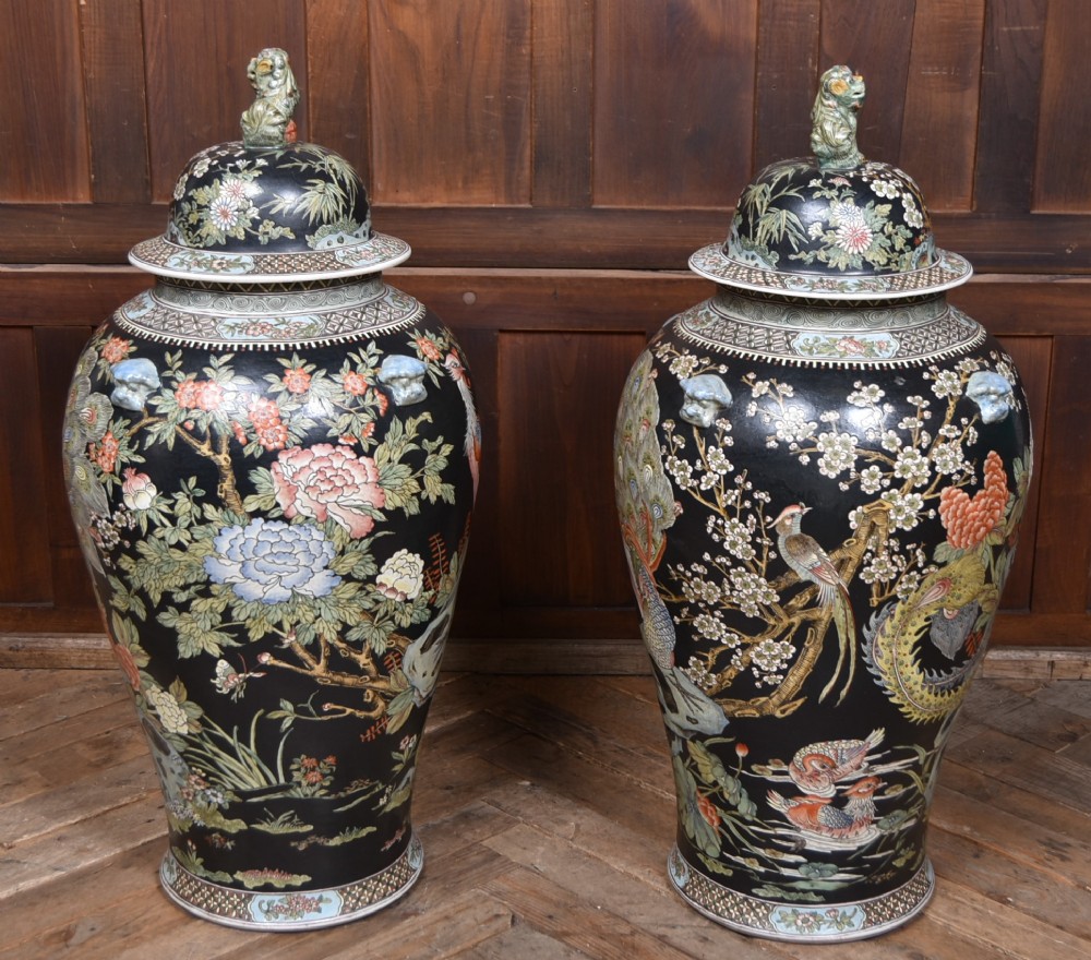 A pair of large black-ground Chinese porcelain floor jars with domed lids topped with foo dog finials and painted peacock, floral, and rockery motifs. View XI