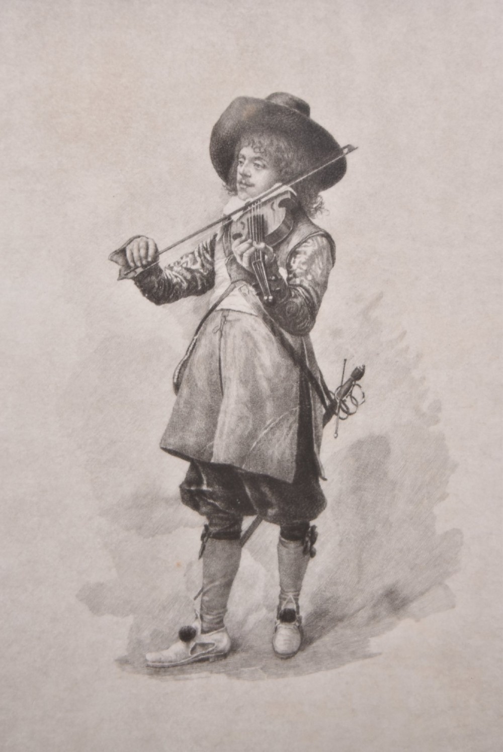 A framed monochrome print depicting a young violinist in period costume, set within a cream mount and an ornate gilded frame. View II