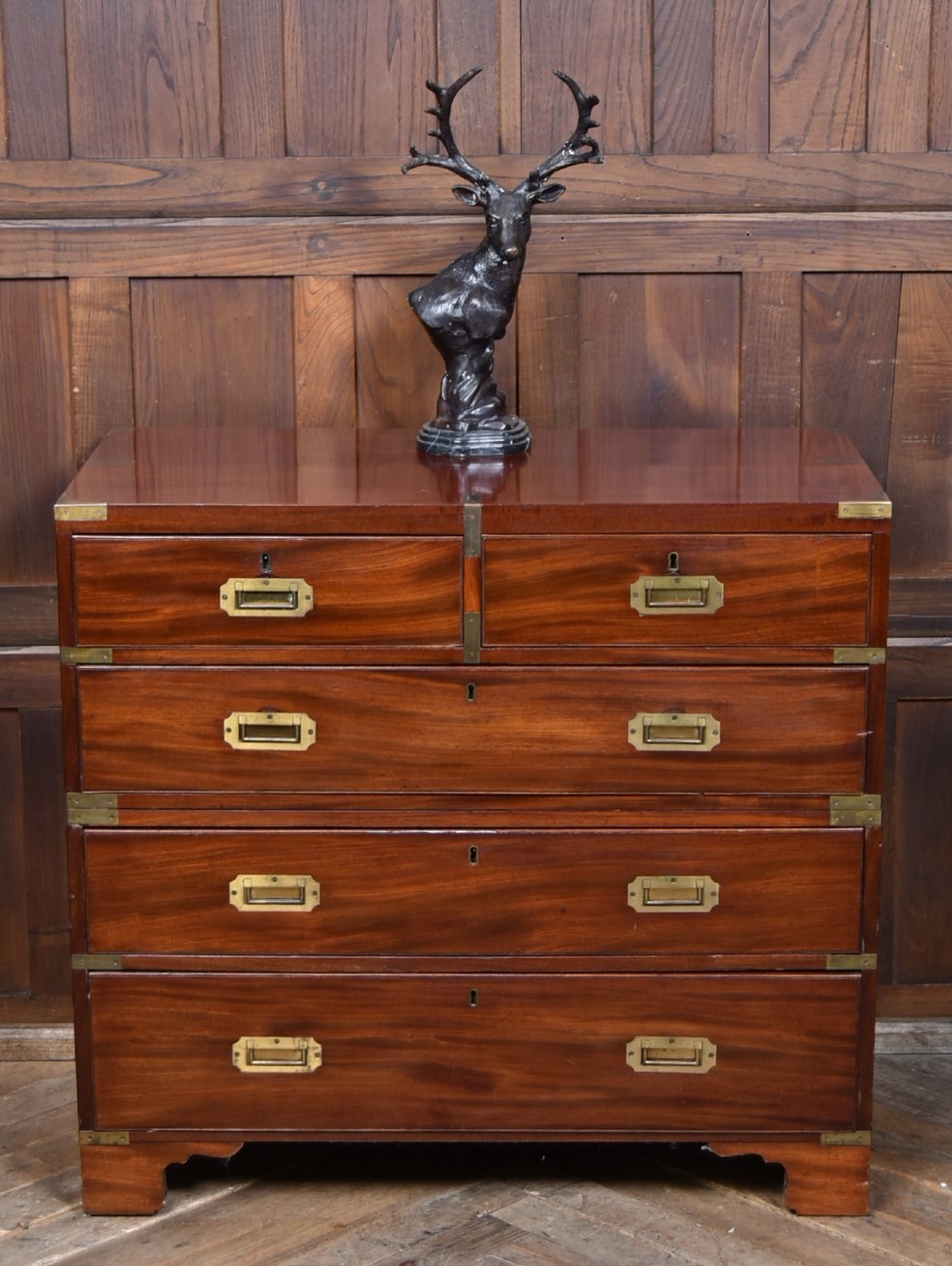 A 19th-century mahogany campaign chest of drawers featuring flush brass handles, corner brackets, and a two-section design.