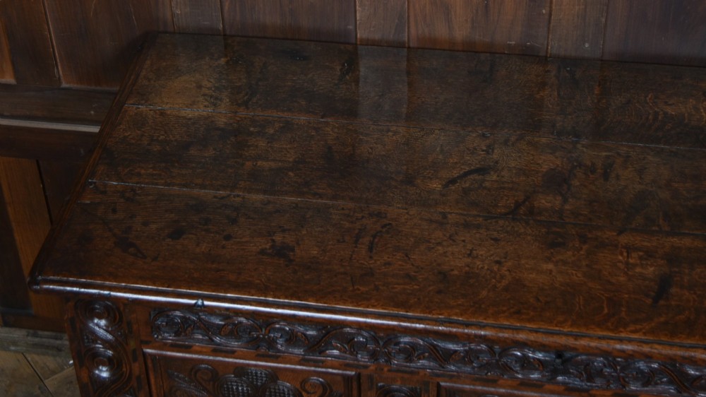 An 18th-century dark oak coffer featuring three carved panels, geometric marquetry inlay, and two lower drawers. View III