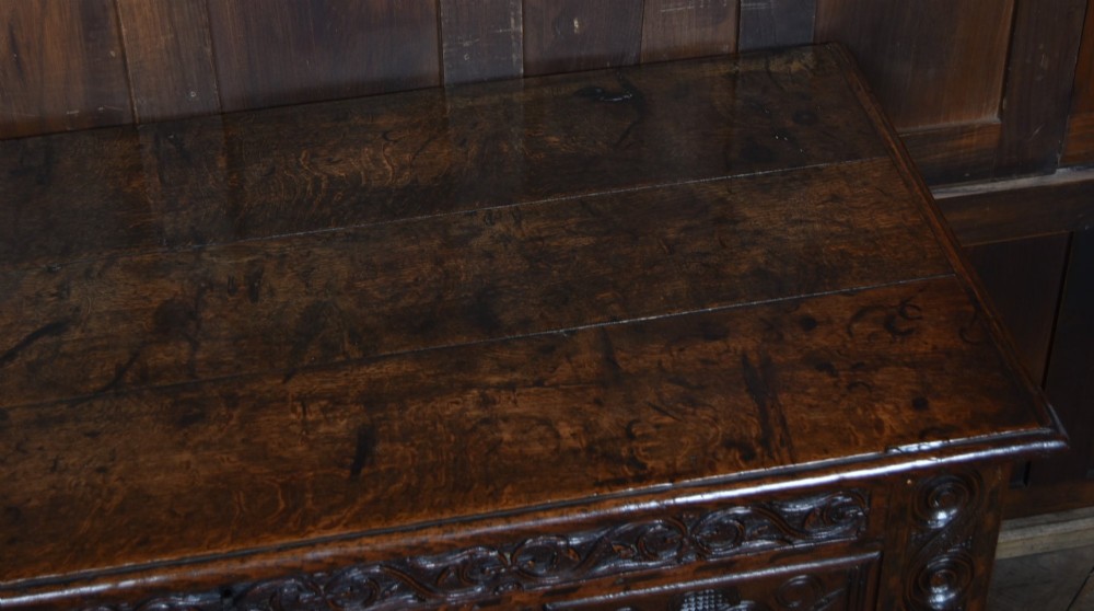 An 18th-century dark oak coffer featuring three carved panels, geometric marquetry inlay, and two lower drawers. View IV