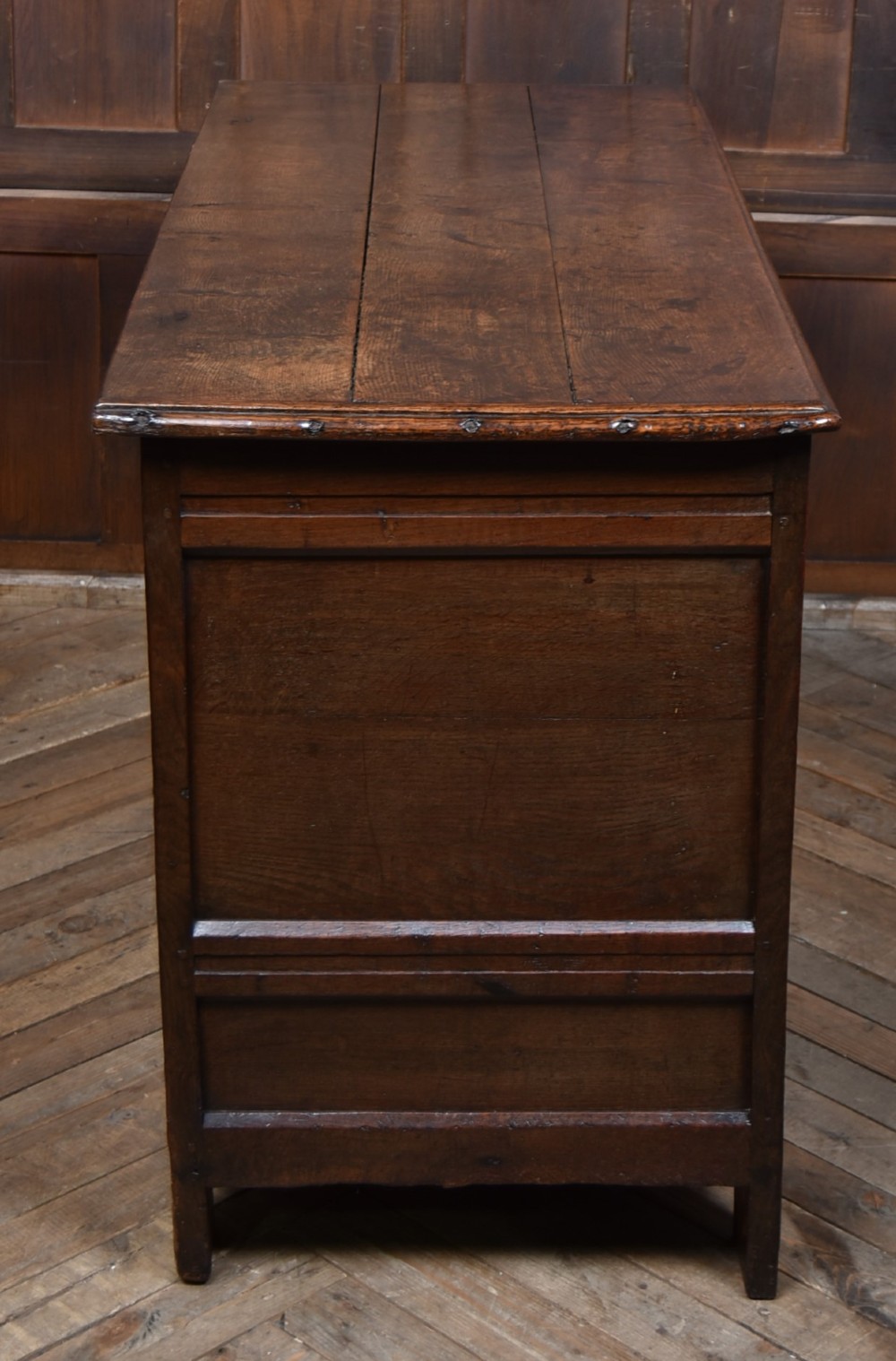 An 18th-century dark oak coffer featuring three carved panels, geometric marquetry inlay, and two lower drawers. View XI