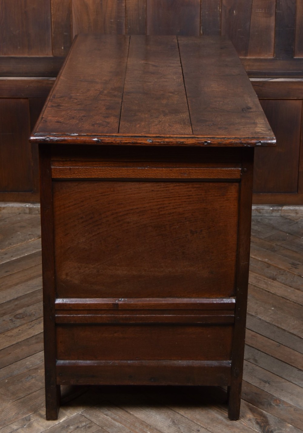 An 18th-century dark oak coffer featuring three carved panels, geometric marquetry inlay, and two lower drawers. View XIII