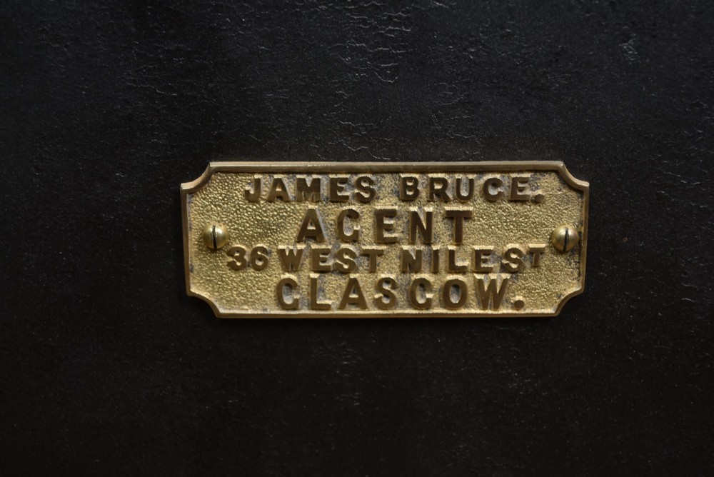 A heavy black painted iron safe featuring a rectangular body, a brass maker plaque for James Bruce of Glasgow, a faceted brass handle, and a brass fire-resisting emblem. View III