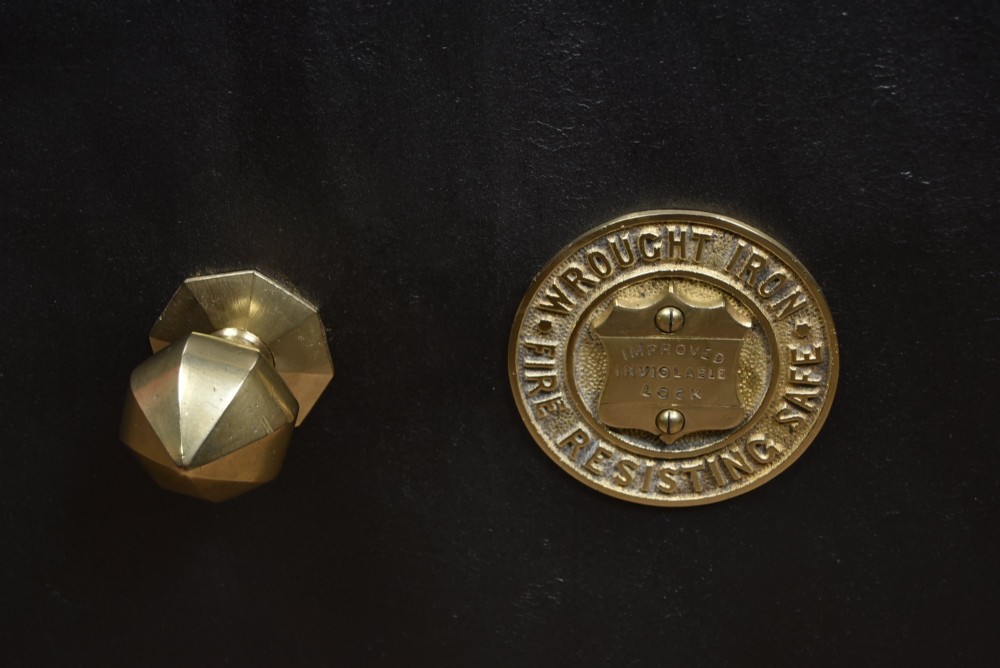 A heavy black painted iron safe featuring a rectangular body, a brass maker plaque for James Bruce of Glasgow, a faceted brass handle, and a brass fire-resisting emblem. View IV
