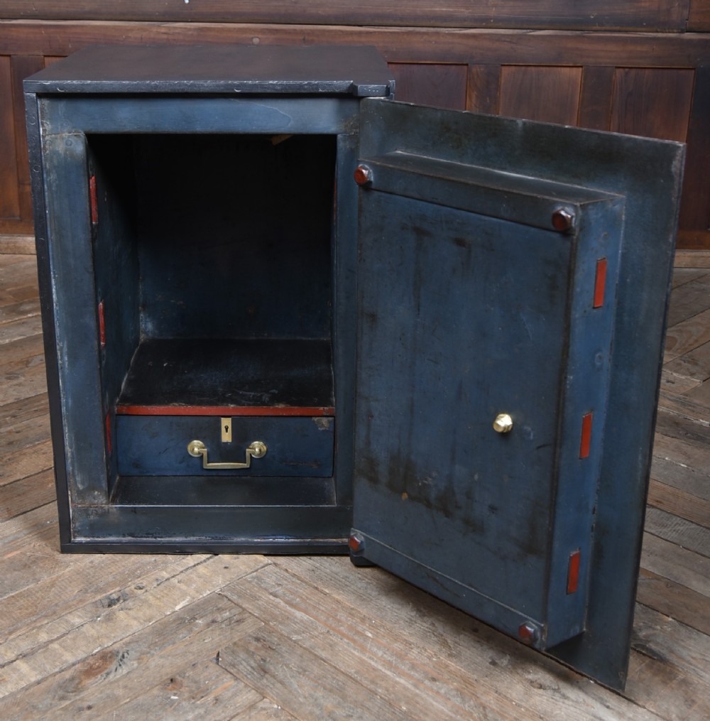 A heavy black painted iron safe featuring a rectangular body, a brass maker plaque for James Bruce of Glasgow, a faceted brass handle, and a brass fire-resisting emblem. View VII