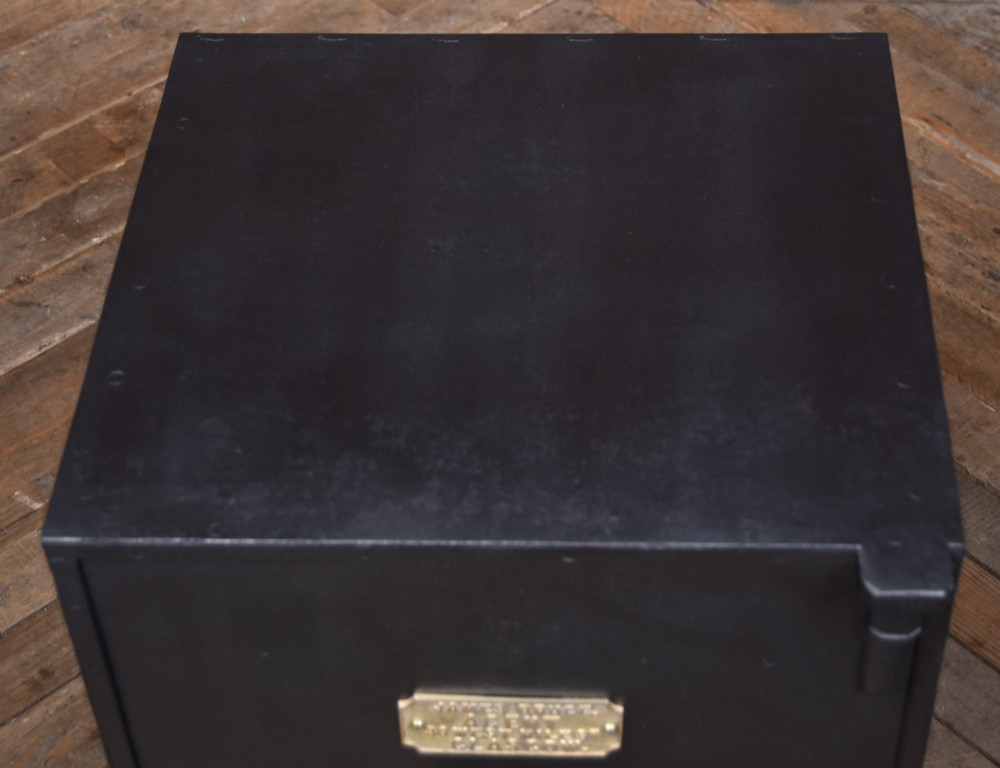 A heavy black painted iron safe featuring a rectangular body, a brass maker plaque for James Bruce of Glasgow, a faceted brass handle, and a brass fire-resisting emblem. View X