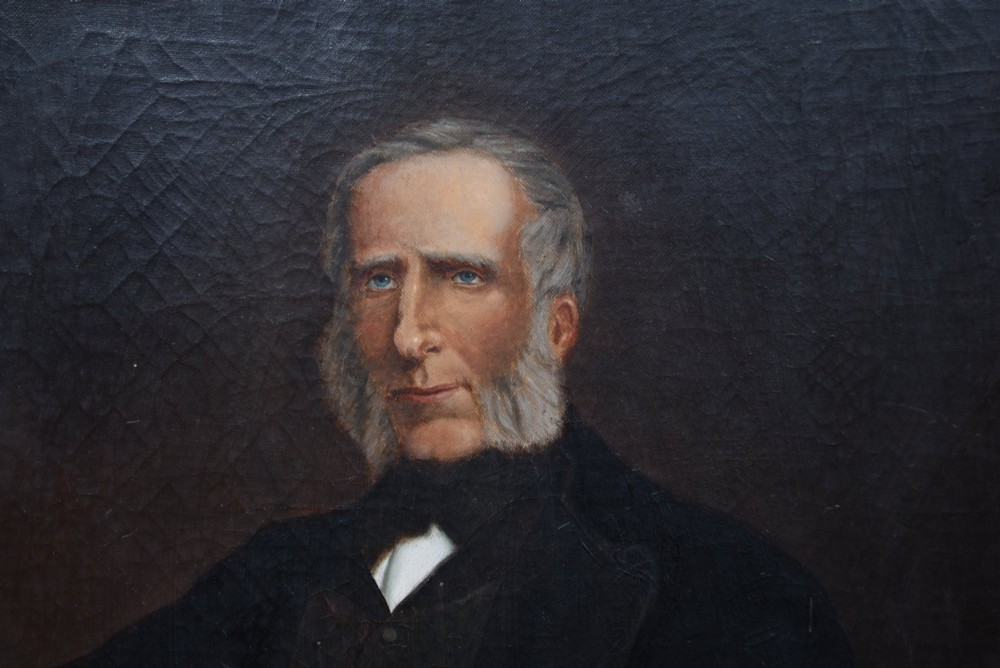 A nineteenth-century oil painting depicting a seated gentleman with sideburns wearing a black coat, framed in a simple dark wooden border. View III