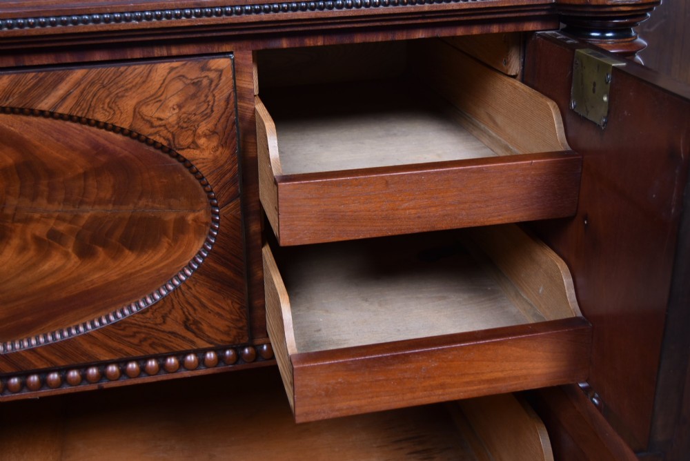 A Victorian mahogany secretaire cabinet featuring Gothic arch decorative panels, turned columns on either side, and flame mahogany veneers. View V