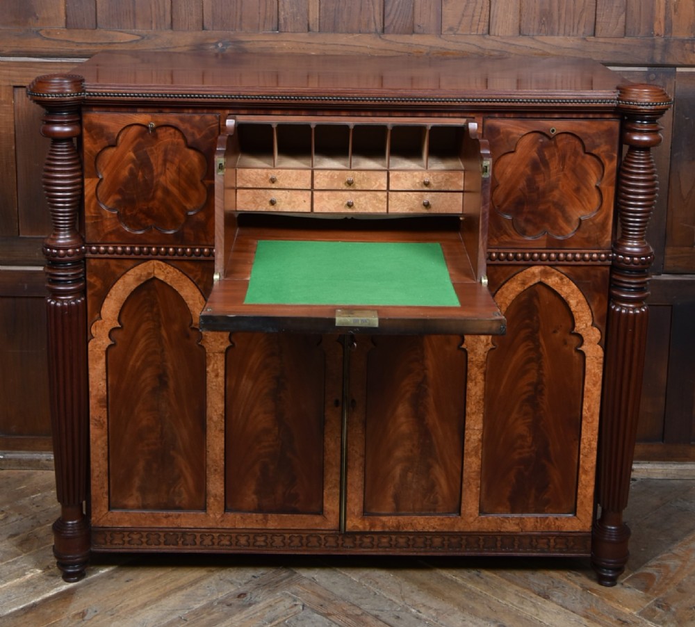 A Victorian mahogany secretaire cabinet featuring Gothic arch decorative panels, turned columns on either side, and flame mahogany veneers. View VI