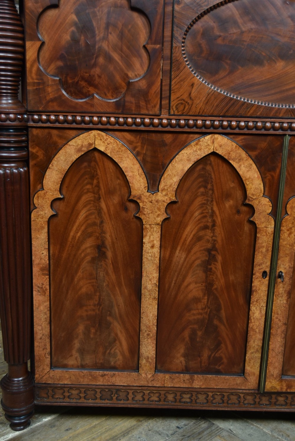 A Victorian mahogany secretaire cabinet featuring Gothic arch decorative panels, turned columns on either side, and flame mahogany veneers. View VIII