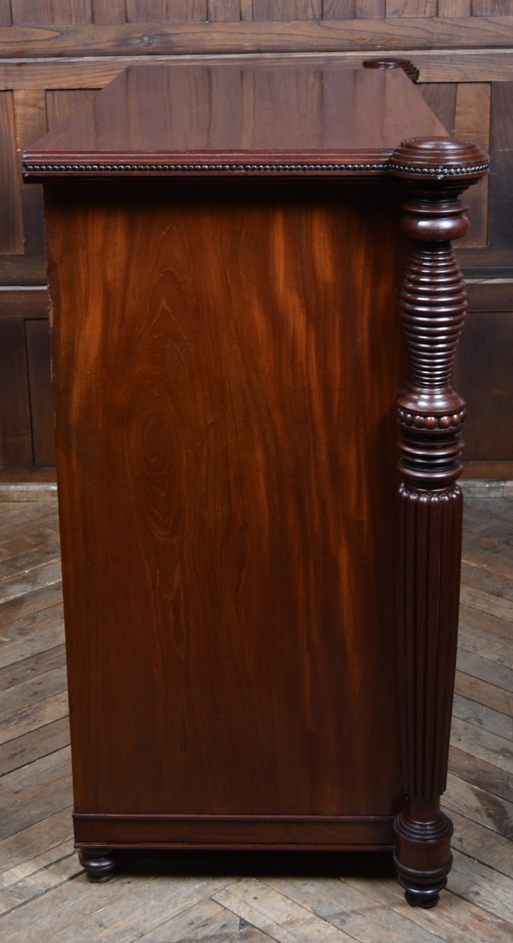 A Victorian mahogany secretaire cabinet featuring Gothic arch decorative panels, turned columns on either side, and flame mahogany veneers. View IX