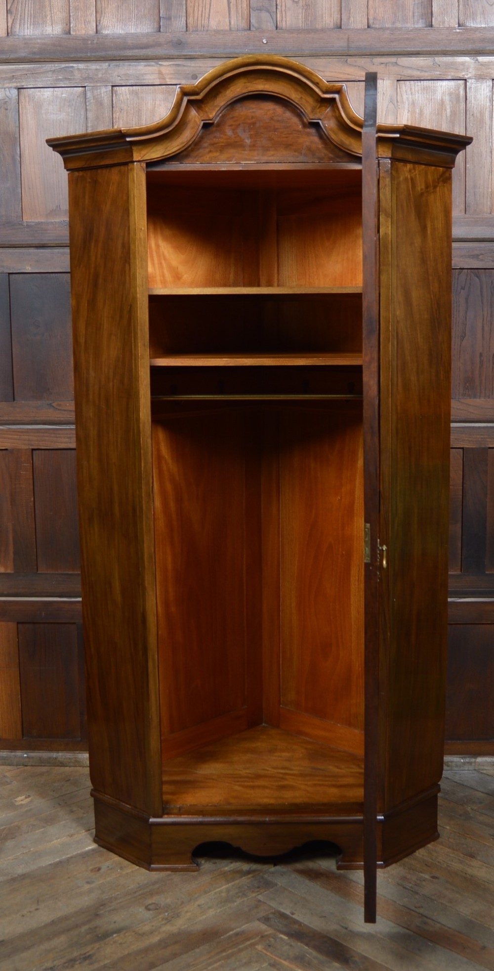 An antique Art Nouveau corner wardrobe crafted from warm walnut wood with an arched pediment, a single panel door featuring floral marquetry, and a shaped plinth base. View VIII