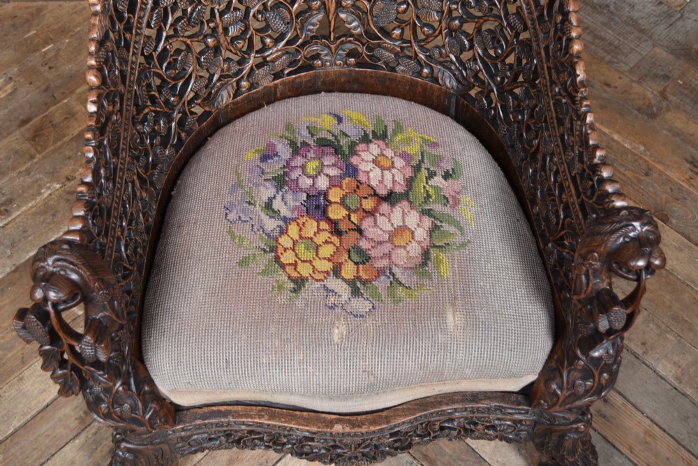 A nineteenth-century dark carved oak armchair featuring intricate openwork thistle motifs across the high arched back and sides, fitted with a floral needlepoint seat cushion. View VII