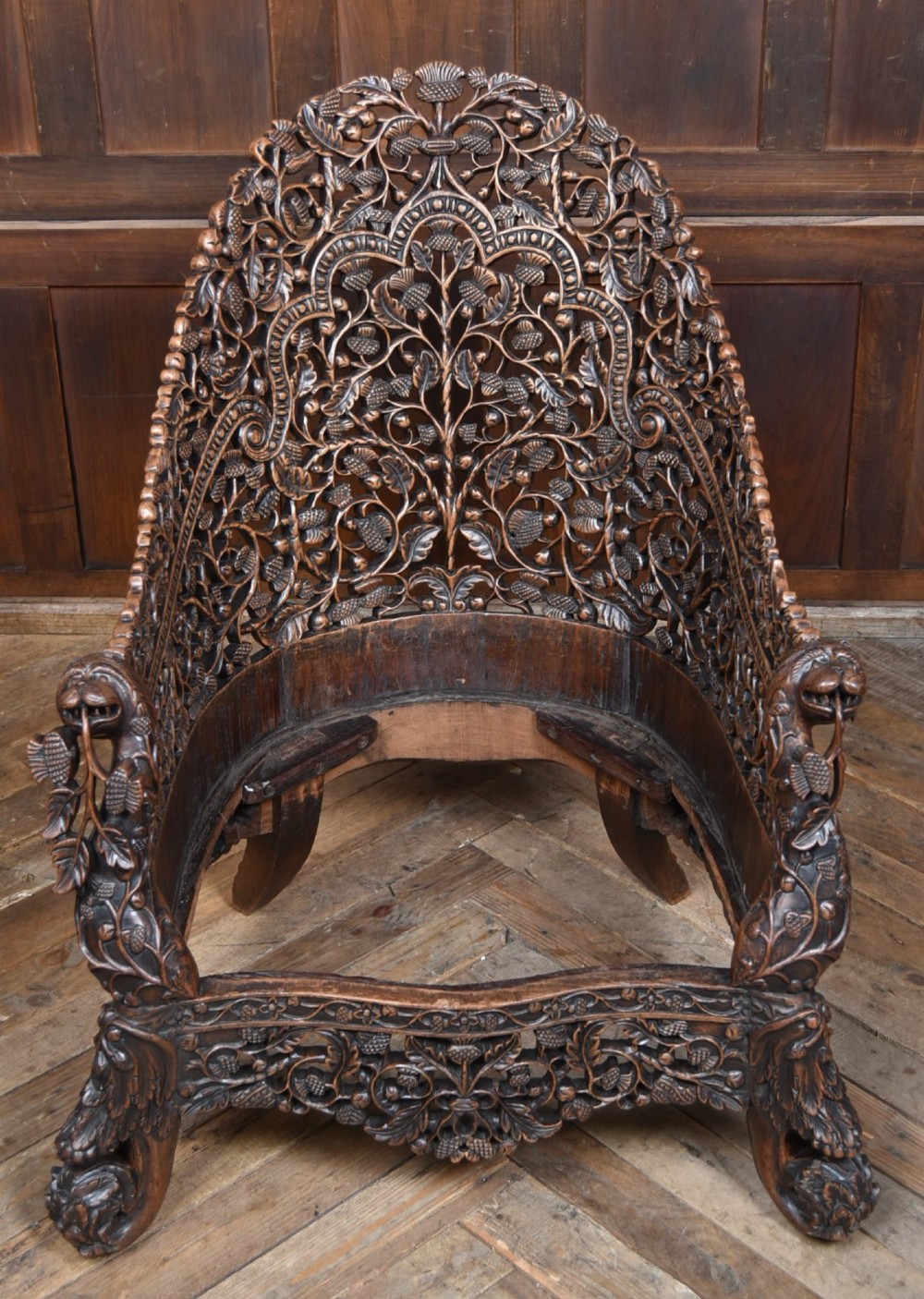 A nineteenth-century dark carved oak armchair featuring intricate openwork thistle motifs across the high arched back and sides, fitted with a floral needlepoint seat cushion. View VIII