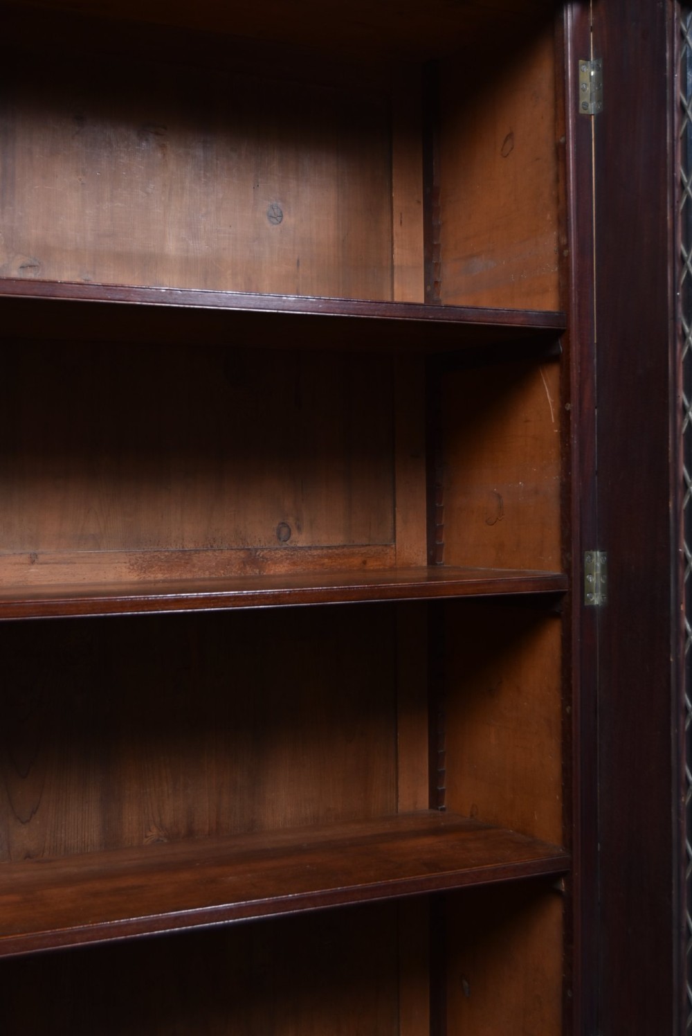 An antique two-part Georgian mahogany bookcase featuring double upper doors with diamond brass wire grilles over lower flame mahogany cupboard doors. View V