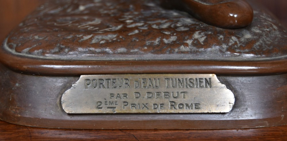 A dark brown patinated bronze sculpture depicting a standing Tunisian water bearer carrying two vessels on a rectangular moulded base. View IV