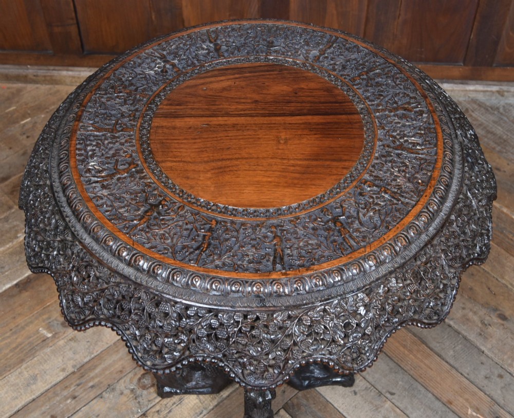 A 19th-century circular Burmese table in dark carved wood with a detailed openwork apron and a sculpted serpent base. View III