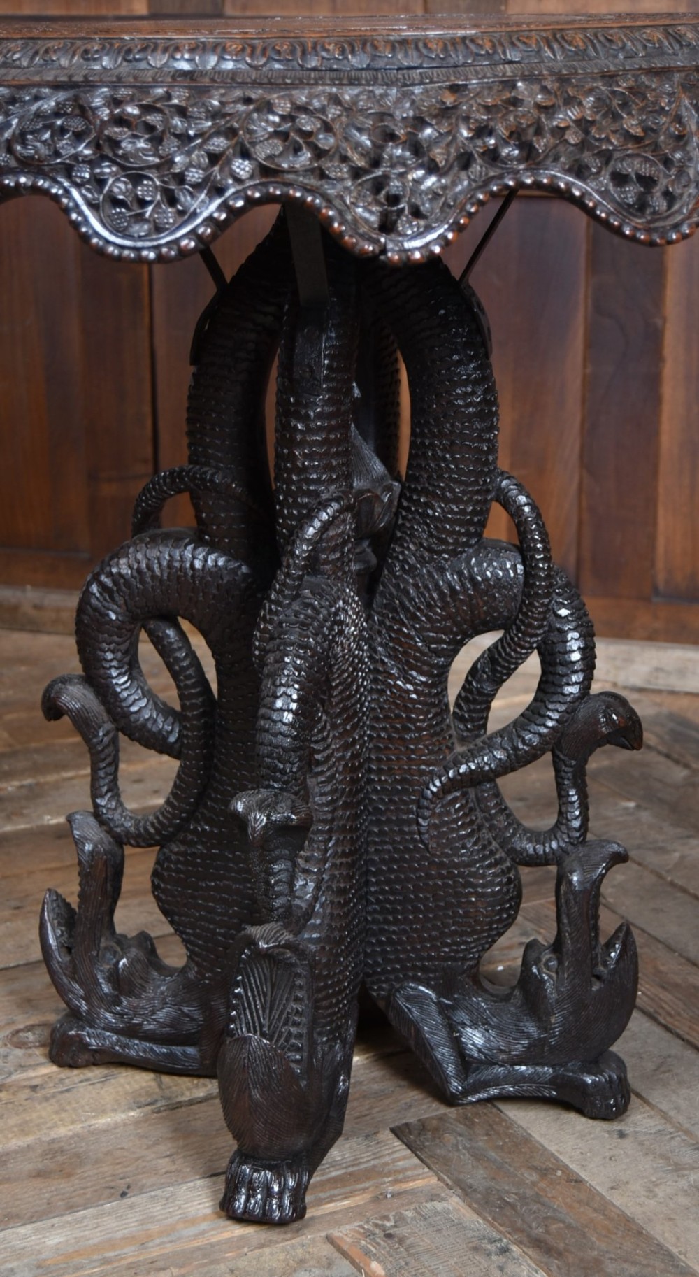A 19th-century circular Burmese table in dark carved wood with a detailed openwork apron and a sculpted serpent base. View IV