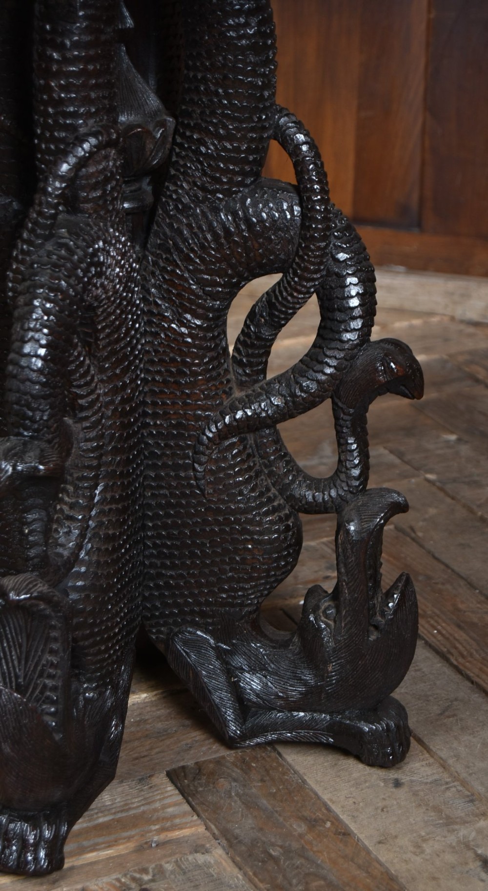 A 19th-century circular Burmese table in dark carved wood with a detailed openwork apron and a sculpted serpent base. View V