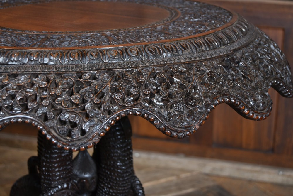 A 19th-century circular Burmese table in dark carved wood with a detailed openwork apron and a sculpted serpent base. View VII