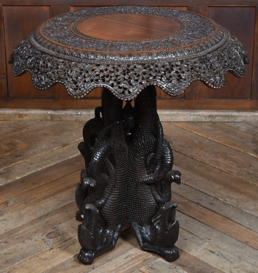 A 19th-century circular Burmese table in dark carved wood with a detailed openwork apron and a sculpted serpent base. View VIII