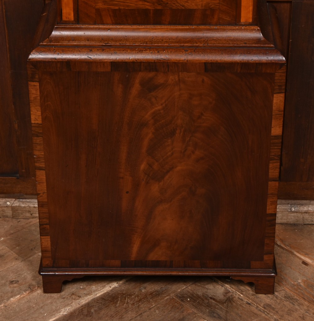 An antique Scottish flame mahogany longcase clock featuring a swan-neck pediment with brass finials and an arched painted dial. View VII