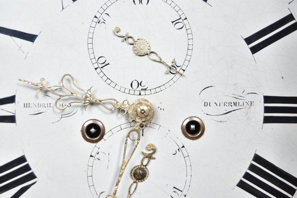 A Scottish mahogany longcase clock featuring a swan-neck pediment with brass finials, a hand-painted dial face, and flame mahogany veneers. View VI