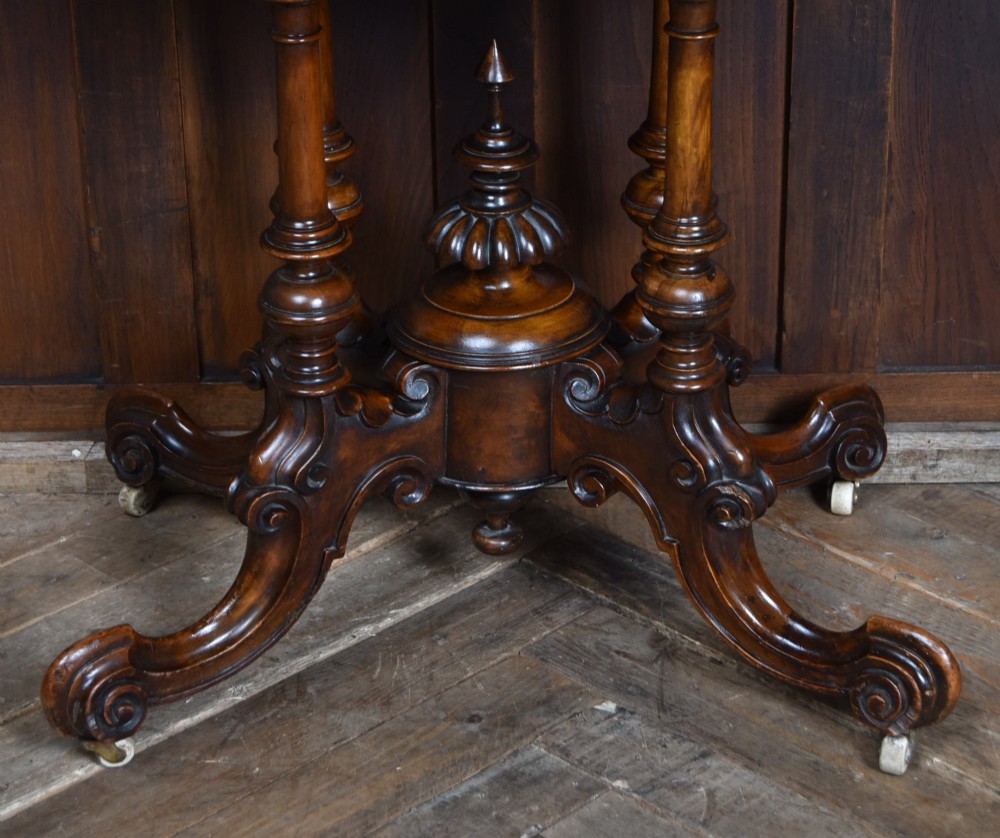 A Victorian burr walnut fold-over games table featuring a semi-circular top, dual turned column pedestal base, carved scroll legs, and ceramic castors. View VII