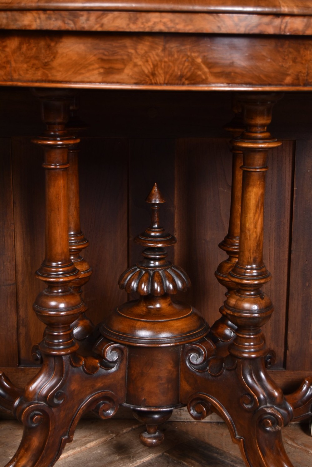 A Victorian burr walnut fold-over games table featuring a semi-circular top, dual turned column pedestal base, carved scroll legs, and ceramic castors. View IX