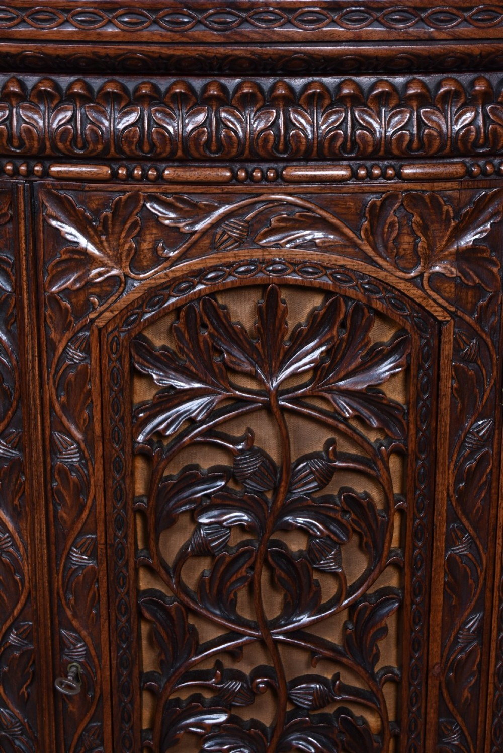 A nineteenth-century padouk wood sideboard featuring high-relief foliate hand-carving across four panelled cupboard doors and a breakfront profile. View XII